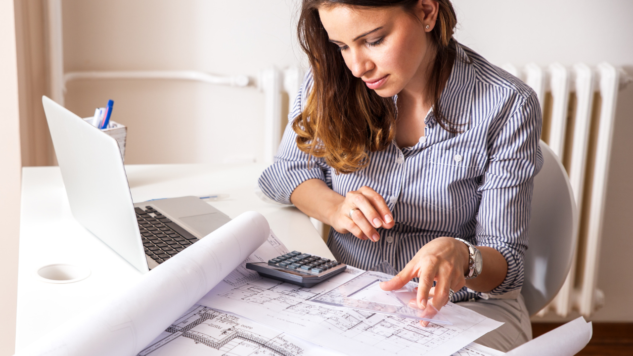 Profesional de diseño de interiores trabajando en un presupuesto detallado para un proyecto de reforma, calculando el coste por hora y materiales